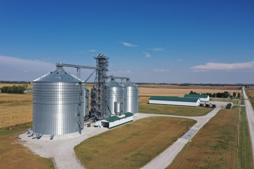 Aerial image of grain silos and long farm buildings with fields in the background